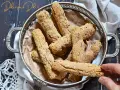 Biscotti senza farina dorati e croccanti, cosparsi di zucchero, in un cestino d'argento. Una mano ne prende uno.