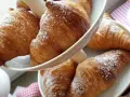 Cornetti fatti in casa, dorati e spolverati di zucchero a velo, invitano a una colazione golosa.