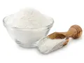 Una ciotola di vetro piena di polvere bianca, probabilmente aluminum starch octenylsuccinate, e un cucchiaio di legno con la stessa polvere.