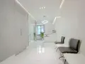 Nowoczesne wnętrze poczekalni kliniki estetycznej z białym recepcjonistą i wygodnymi fotelami.