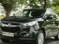 Czarny Hyundai ix35 jedzie drogą wśród zieleni.