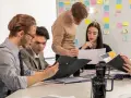 Studenci analizują wykresy, przygotowując się do zajęć z handlu międzynarodowego. Na tablicy notatki i pomysły.
