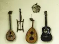Verschiedene Saiteninstrumente und ein Tamburin hängen an der Wand. Seit wann gibt es Gitarren? Die Geschichte der Gitarre reicht weit zurück.