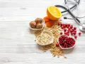 Sposób babci na obniżenie cholesterolu: orzechy, owsianka, żurawina, granat, pomarańcza i suszone morele. Stetoskop symbolizuje zdrowie.