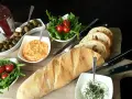 Eine köstliche italienische Brotzeit mit Baguette, Oliven, Tomaten, Rucola und Dips.