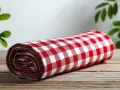 Tovaglia a quadri rossi e bianchi arrotolata su un tavolo di legno. Cos'è la fantasia? È l'immaginazione che crea scenari, come un picnic in un prato.
