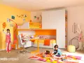 Una vivace stanza dei giochi bambini con letto a castello, scrivania e un bambino che gioca sul tappeto colorato.