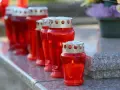 Rote Grablichter brennen auf einem Grabstein. Am 1. November, dem Feiertag Allerheiligen, werden sie zum Gedenken entzündet.