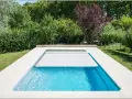 Piscina con cubierta automática, lista para reformar y disfrutar del verano. Rodeada de vegetación exuberante.