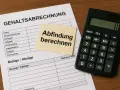 Gehaltsabrechnung mit Notiz "Abfindung berechnen" und Taschenrechner. Wichtig für die Berechnung der Abfindung bei einem Minijob.