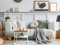 Un plaid gris drapé sur un canapé vert menthe, ajoutant une touche cosy. Idée pour comment mettre un plaid sur un canapé.