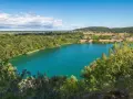 Turkusowe wapnica jezioro otoczone zielonymi lasami i wzgórzami.