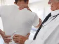 Lekarz bada pacjenta z bólem pleców. Może to być początek leczenia z aclexa.