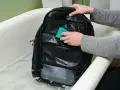 Se puede lavar una mochila en la lavadora. Alguien limpia una mochila negra en una bañera con agua y jabón.