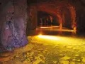 Podziemne miasto Osówka skrywa mroczne tunele z wodą odbijającą złote światło.
