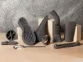 SLS TPU 3D printed objects: shoe sole, fan, cone, pipe, brace, and a timing belt.
