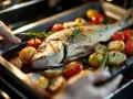 Un delicioso pargo al horno con tomates cherry, patatas y romero, listo para ser servido.