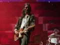 Nick Valensi spielt Gitarre auf einer Bühne, im Hintergrund ein Schlagzeuger.