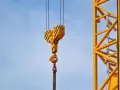 Żółty hak żurawia z łańcuchem na tle błękitnego nieba.