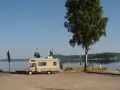 Husbil vid vattnet med figurer på taket, redo för året runt camping. En vacker plats för avkoppling.