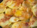 Rodajas de patatas fritas al horno, doradas y espolvoreadas con pimentón.