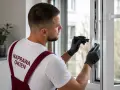 Fachowiec z latarką sprawdza mechanizm, bo okno nie chce się zamknąć. Naprawa okien to jego specjalność.