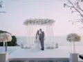 Para młoda pozuje pod kwiecistym baldachimem. Piękna sceneria na zapowiedzi przedślubne z widokiem na ocean.