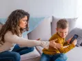 Genervte Mutter streitet mit Sohn, der sein Handy nicht abgeben will. Mögliche ADHS-Erziehungsfehler im Fokus.