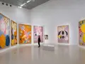En person betraktar en samling färgstarka, abstrakta målningar av Hilma af Klint i ett ljust galleri.
