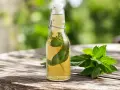 Une bouteille de sirop de menthe maison, avec des feuilles de menthe fraîche à côté, sur une table en bois.
