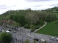 Grüne Hügel und Bäume im Volkspark Prenzlauer Berg. Autos parken am Straßenrand, eine Treppe führt einen Hang hinauf.