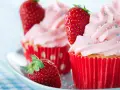 Erdbeer cupcakes mit rosa Zuckerguss und frischen Erdbeeren, verziert mit bunten Streuseln.