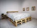 Un letto fai da te economico realizzato con pallet di legno, con un copriletto bianco e nero a tema alfabetico.