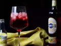 Orzeźwiający martini z tonikiem, z lodem i owocowym akcentem, obok butelki toniku i butelki Martini.