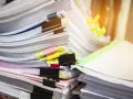 Stosy dokumentów z kolorowymi spinaczami i zakładkami.