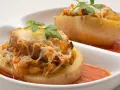 Patatas rellenas de carne de la abuela, gratinadas con queso y perejil, servidas con salsa de tomate.