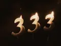 Trzy świeczki w kształcie cyfry 3, płonące w ciemności. Liczba 333 znaczenie, symbolizująca harmonię i równowagę.