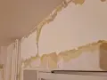 Tapeten flagnar och visar lager av gammal färg och papper. En renovering är på gång, där man förbereder för att måla på tapet.