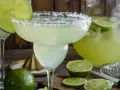 Spicy Margarita przepis: orzeźwiający drink z solą na brzegu kieliszka, limonkami i dzbankiem pełnym zielonego napoju.