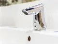 Elegancka bateria umywalkowa z korkiem, wykonana z chromowanego metalu, lśni na białej ceramice.
