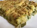 Fetta di polpettone genovese, con patate e verdure verdi, cotto al forno e cosparso di pangrattato croccante.