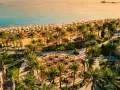Rajska plaża w Makadi Bay z rzędami leżaków i palm. W oddali błękitne morze i statki.