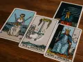 Cartas de tarot: el Rey de Espadas, el As de Espadas y el 9 de espadas, con una figura afligida al fondo.