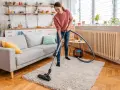 A woman vacuums a fluffy rug, demonstrating how to clean a rug for a fresh, tidy living room.