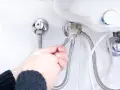 Mani con chiave inglese che lavorano su un raccordo dello scaldabagno, un passo per imparare come svuotare lo scaldabagno.