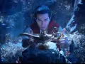 Aladyn, w mrocznej jaskini pełnej skarbów, trzymając magiczną lampę.
