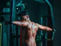 Man svettas under ett träningspass med flyes med hantlar i ett mörkt gym.