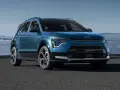 Niebieski Kia Niro Hybrid z nowoczesnym designem, zaparkowany na tle mglistego krajobrazu.