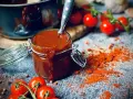 Ein Glas mit selbstgemachter bbq sauce, daneben Kirschtomaten und Paprikapulver. Perfekt für den Grill!