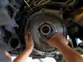 Mechanik dokonuje wymiany dwumasy w samochodzie, pracując przy skrzyni biegów.